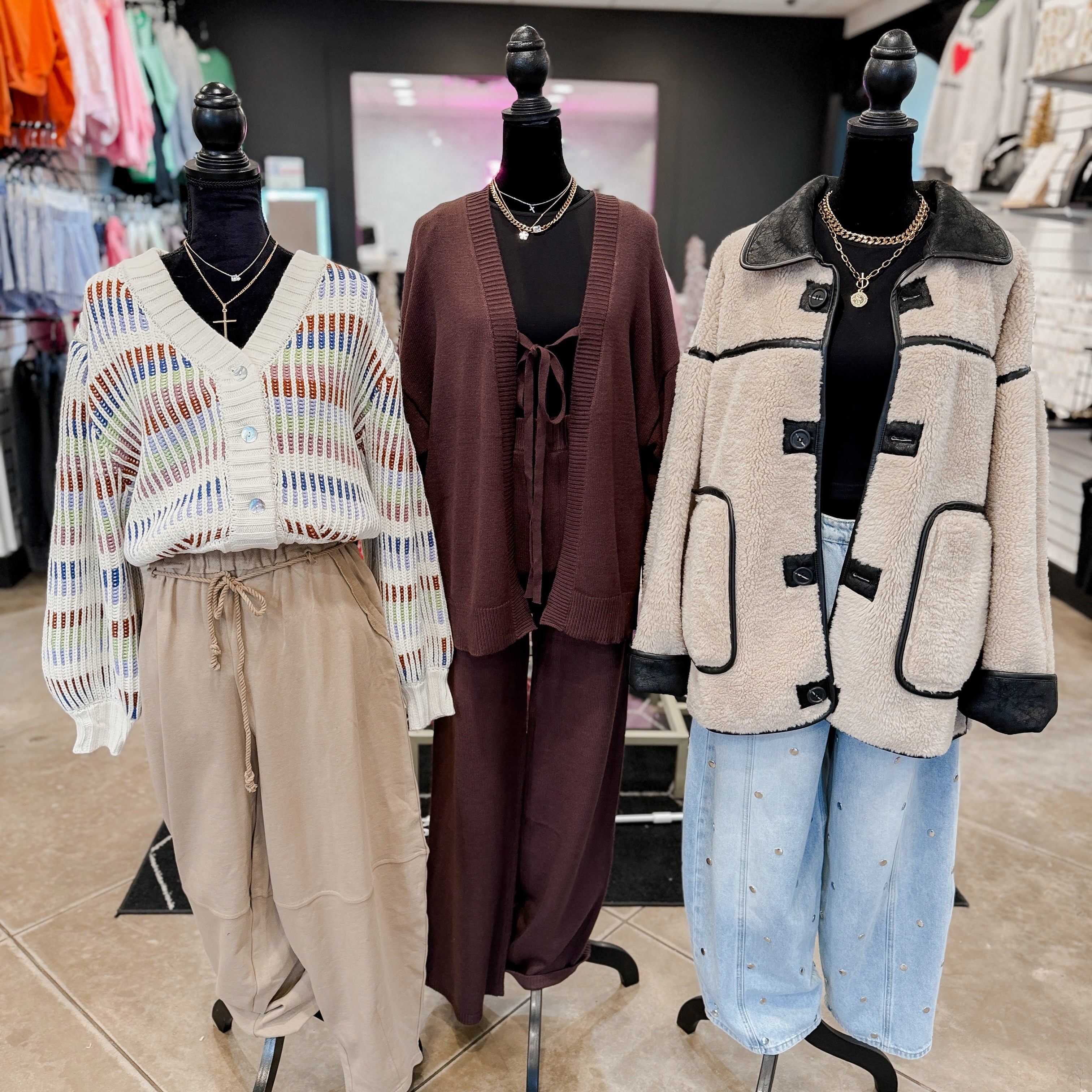 Three mannequins dressed in stylish outfits with accessories in a store setting.